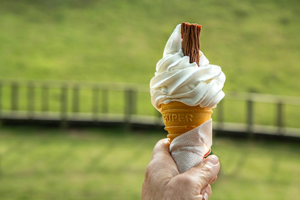 Enjoying a soft vanilla ice cream cone with a chocolate flake on a sunny day.